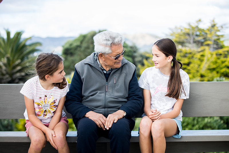 A grandfather sits with his two granddaughters and listens as one of his granddaughter speaks.